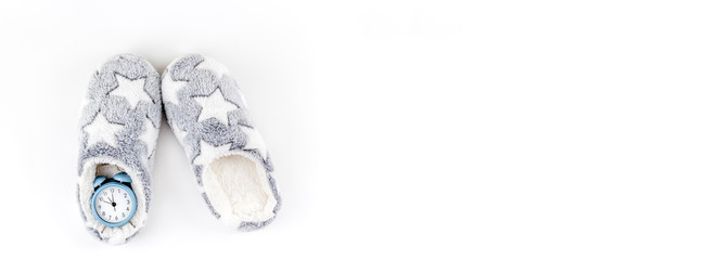 Soft fluffy slippers and blue alarm clock