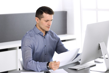 Businessman working with computer in modern office. Headshot of male entrepreneur or company director at workplace. Business concept