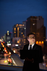 Handsome Persian businessman against view of the city at night