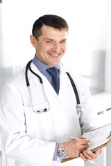 Doctor man using clipboard for filling up medication history records. Perfect medical service in clinic. Physician at work in hospital. Medicine and healthcare concepts