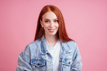 Fototapeta premium redhaired ginger woman wearing white cotton t-shirt , demin jeans jacket and small crystal jewel microdermal on neck ,smile in studio pink background