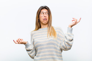 young pretty woman shrugging with a dumb, crazy, confused, puzzled expression, feeling annoyed and...