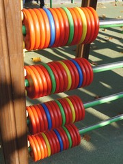 Vertical photo of four rows of multicolor wooden disks for counting at a kids' playground.