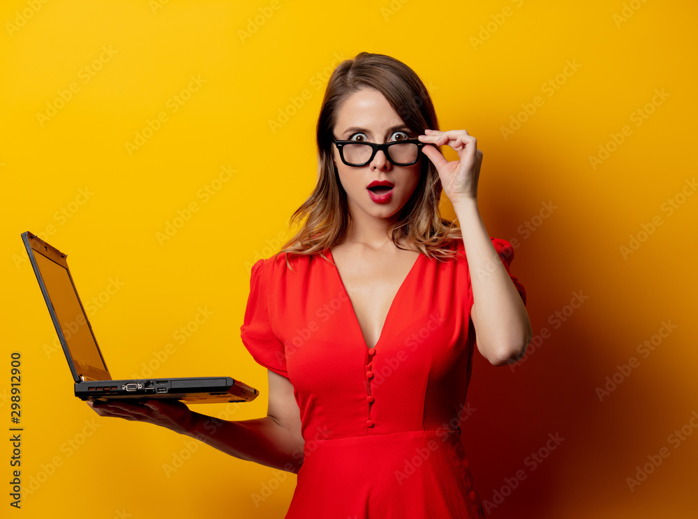 Poster beautiful woman in red dress with laptop computer on yellow background