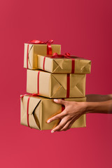 cropped view of african american woman holding gift boxes isolated on red