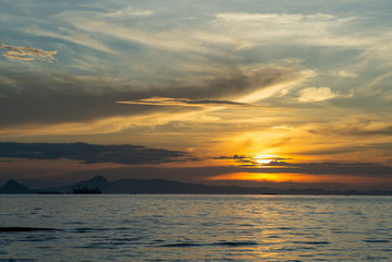 Obraz premium Silhouette of big ship with shadow of island and orange light of sunrise in background