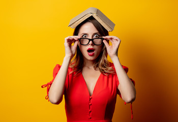 Beautiful woman in red dress with book on yellow background