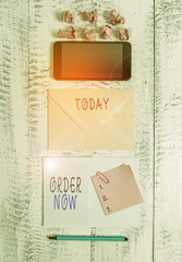 Handwriting text writing Order Now. Conceptual photo the activity of asking for goods or services from a company Envelop smartphone notepad note clip marker paper balls wooden background