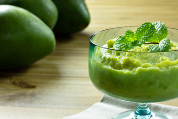 avocado dessert in green glass jar with mint on top over wooden table