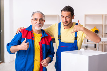 Two contractors repairing fridge at workshop