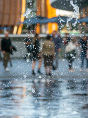 Water drops with selective focus, sprinkled from a fountain on the floor, with people in the blurred background