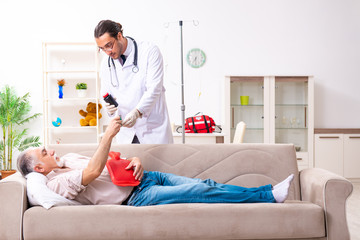 Young male doctor visiting old patient at home