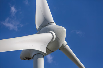 View of a wind turbine on top of mountains, blue sky as background