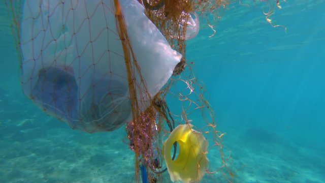 various disposed plastic trapped in a fishing net, floating in the sea