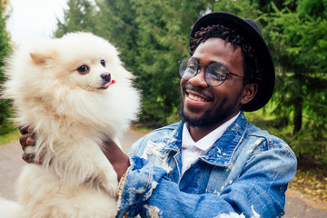 afro man hugging his fluffy spitz in park