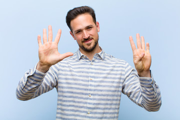 young handsome man smiling and looking friendly, showing number nine or ninth with hand forward,...