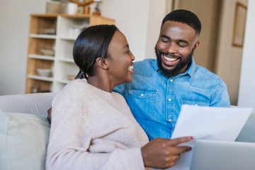 Laughing African American couple doing online banking at home