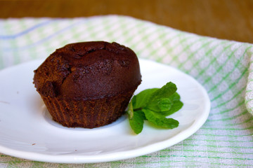 Chocolate Muffin with Mint Leaf on the Saucer in the Kitchen