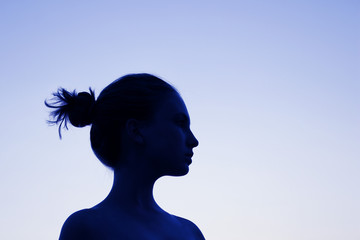 Portrait of a young girl looking to the side. Silhouette of young woman, toned blue. People, travel concept.