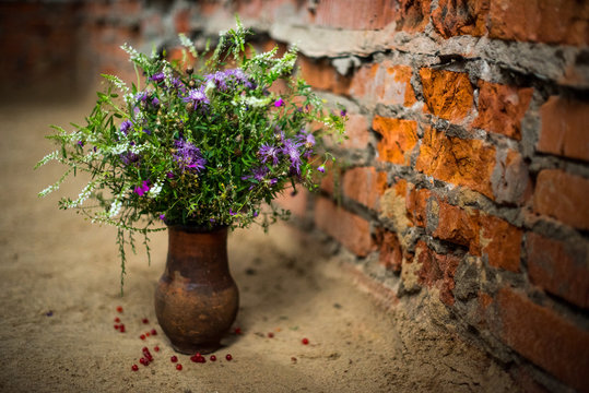 bouquet of flowers in a clay pot on a brick wall background