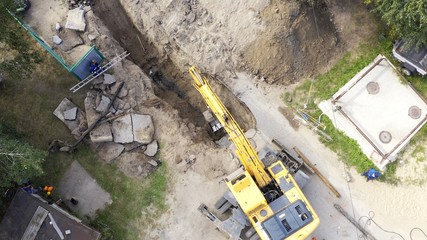 Excavator and workers digging a pipe hole
