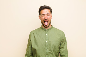 young handsome man with cheerful, carefree, rebellious attitude, joking and sticking tongue out,...