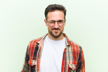young handsome man looking happy and friendly, smiling and winking an eye at you with a positive...