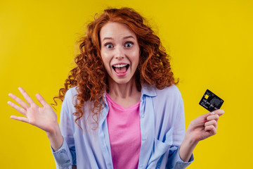 redhaired ginger woman with curly red hair having fun in studio yellow background,holding credit...