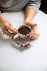 White porcelain tea cup on a white background in womans hands