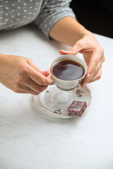 White porcelain tea cup on a white background in womans hands