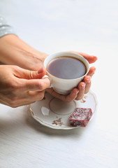White porcelain tea cup on a white background in womans hands