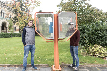 Young man making a a call in a telephone booth