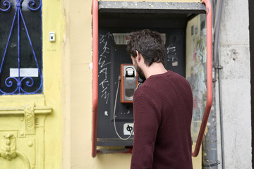 Young man making a a call in a telephone booth