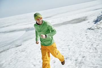 Fototapeta na wymiar Young adult man outdoors running in icy landscape