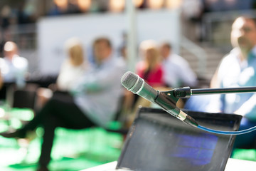 Microphone in focus against blurred people at business presentation or workshop