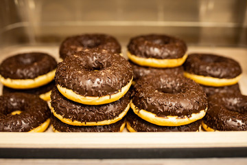 a lot of chocolate-coated donuts on a store counter