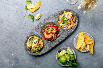 CEVICHE. Three colorful shrimps ceviche with mango, avocado and tomatoes. Latin American Mexican Peruvian Ecuadorian food. Served with white wine and banana chips