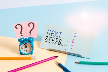 Writing note showing Next Steps. Business concept for something you do or plan after you ve finished something else Mini size alarm clock beside stationary on pastel backdrop