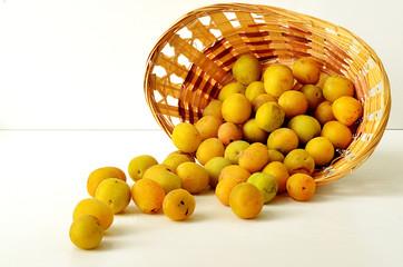 Yellow ripe plum in a wicker basket on a white background. Ripe plum. Yellow plum. Collected plum in the basket.