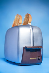 Vintage toaster with toast popping out isolated on a blue background