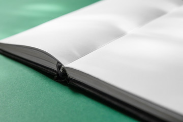 An open book on a table with spots of sunlight.