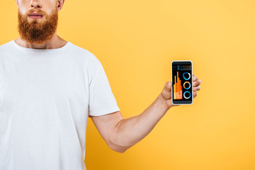 cropped view of bearded man showing smartphone with graphics, isolated on yellow