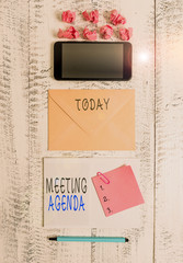 Handwriting text writing Meeting Agenda. Conceptual photo items that participants hope to accomplish at a meeting Envelop smartphone notepad note clip marker paper balls wooden background