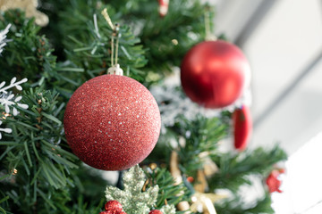 Red ball hanging from a decorated Christmas tree.