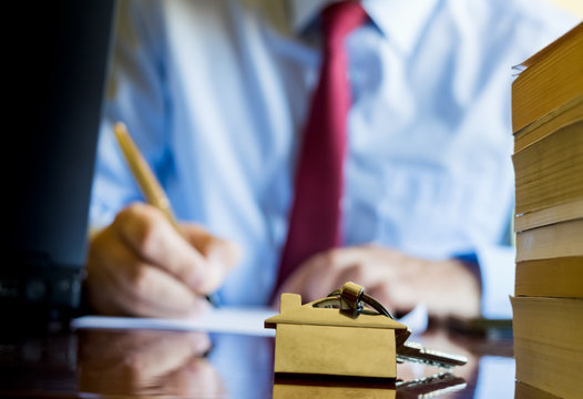 Home key with house keyring with bllured estate agent signing a contract