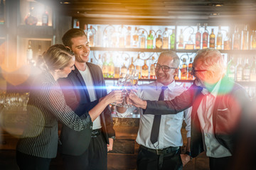 Toasting to success concept.Group of business people toast with champagne and smiling while standing close to each in bar.Friends clinking and toasting with glasses of champagne in lounge.