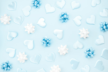 Fototapeta na wymiar Beautiful silk hearts, white and blue holiday bows on a blue background, pastel colors . Celebrate concept. Flat lay .