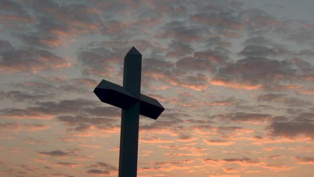 large Christian Cross at sunset with clouds in the sky. 