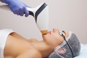 Anti-aging procedures. Skin care concept. Woman receiving facial beauty treatment, removing...