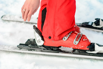 Sport set of skis, boots and sticks in red on woman's leg close up.